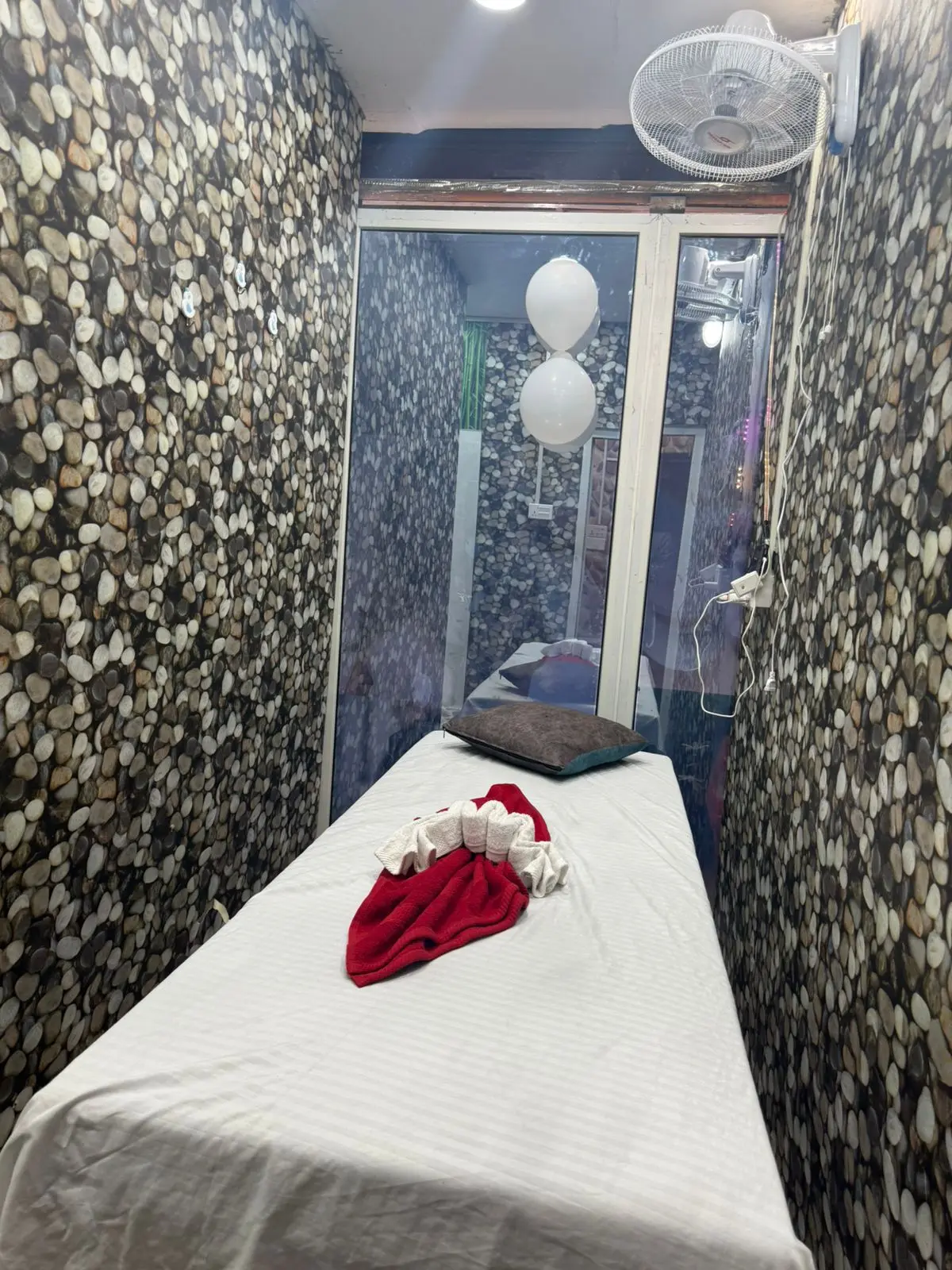 A second pebble-walled treatment room arranged for a single guest