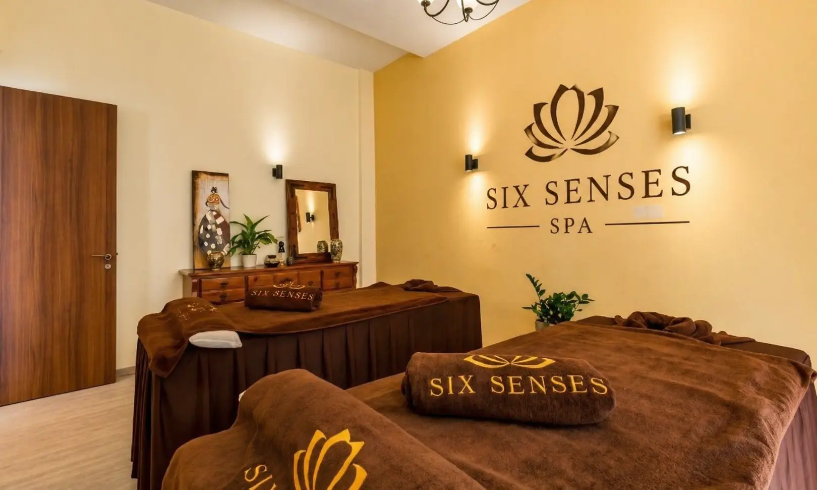 The signature Six Sense treatment room with embroidered massage blankets under a lotus wall mark