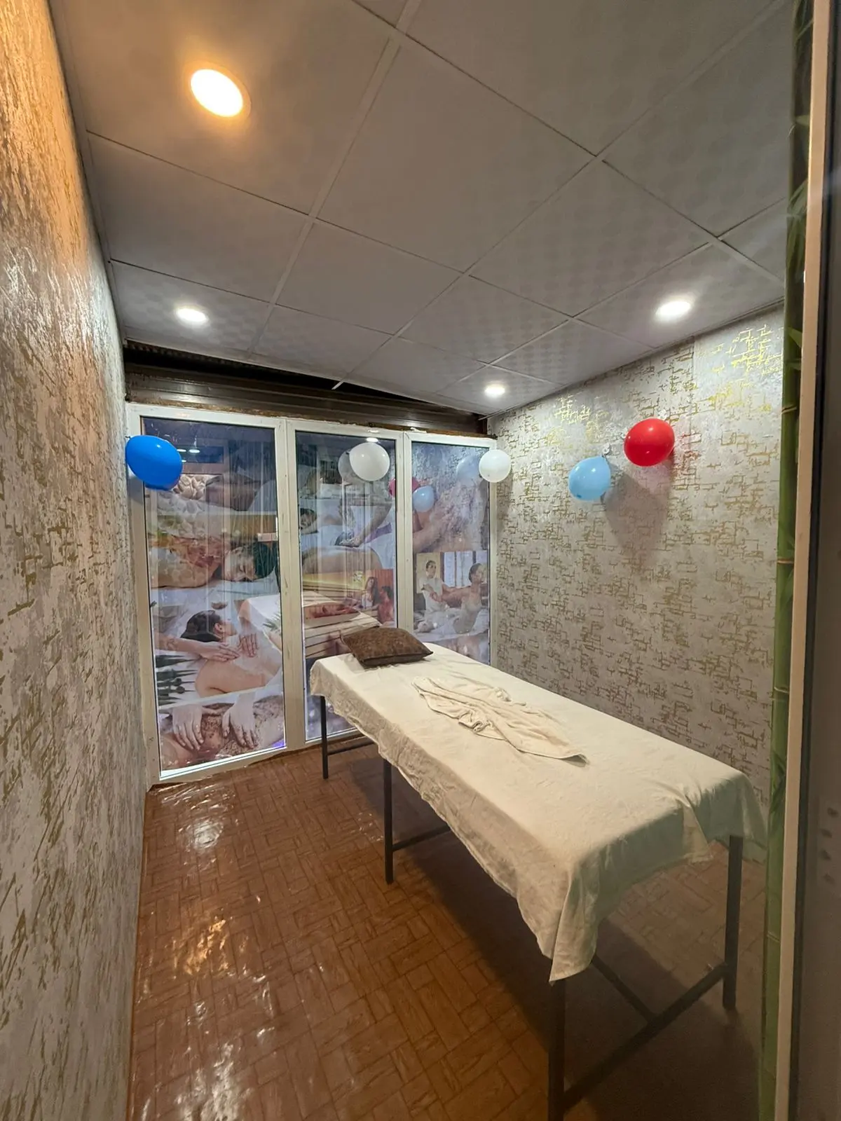 Treatment room with feature wallpaper and posters showing common spa treatments